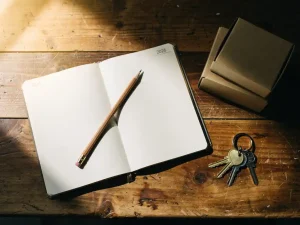 Open 2026-planner met handgeschreven verhuisdata, potlood, gelabelde verhuisdozen en huissleutels op houten bureau in warm natuurlijk licht.